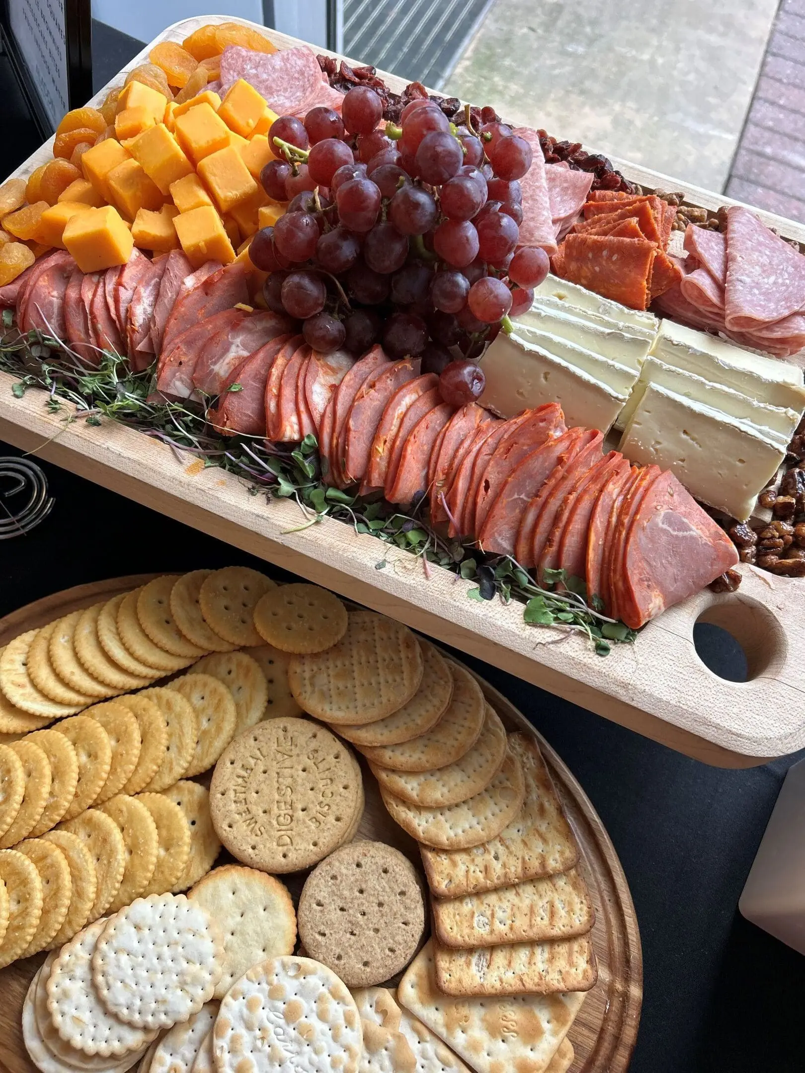 an overhead image of a charcuterie board with various meats, fruit, and cheeses