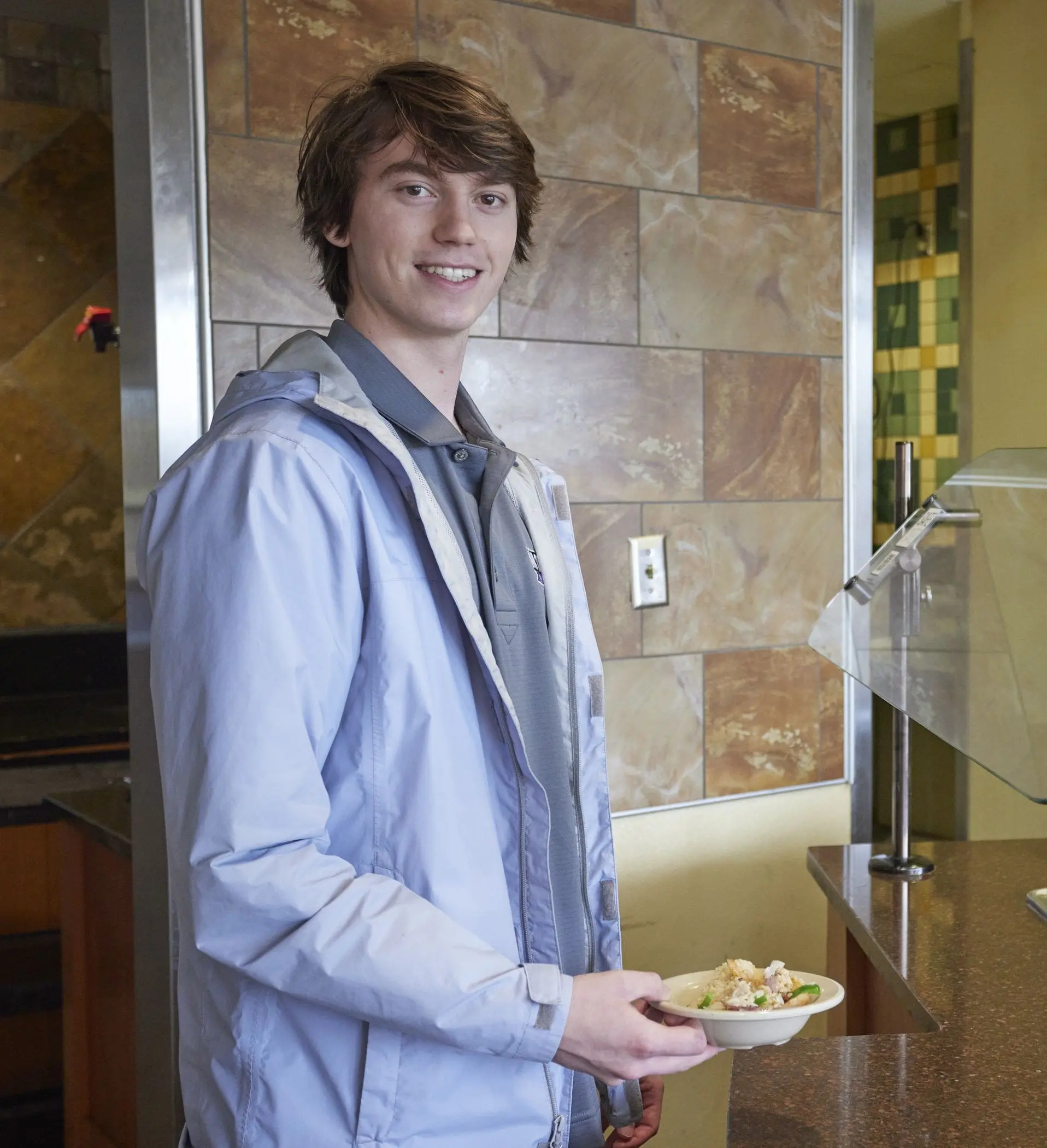 Student holding plate of food and smiling