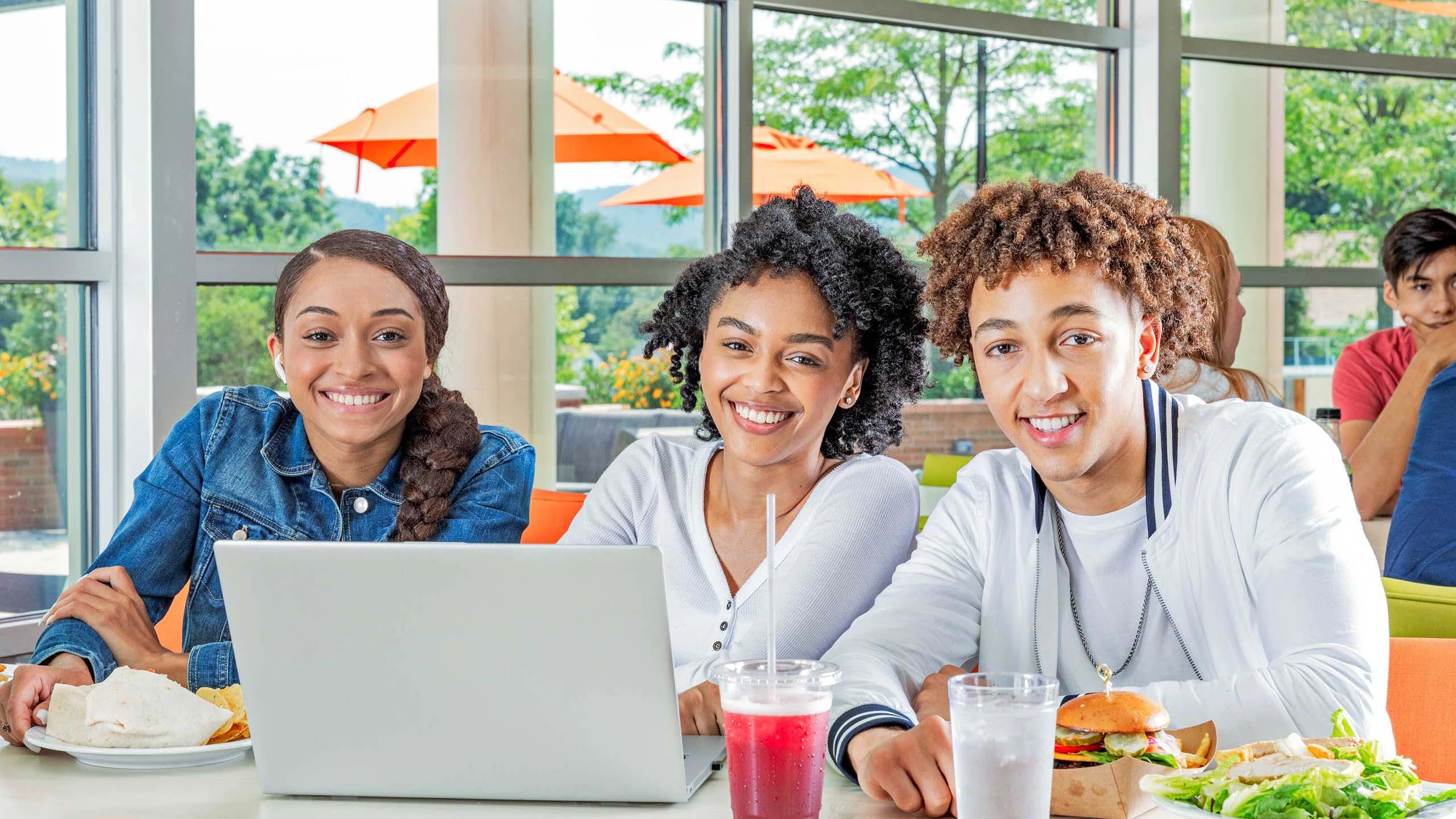 Three students sitting at table smiling